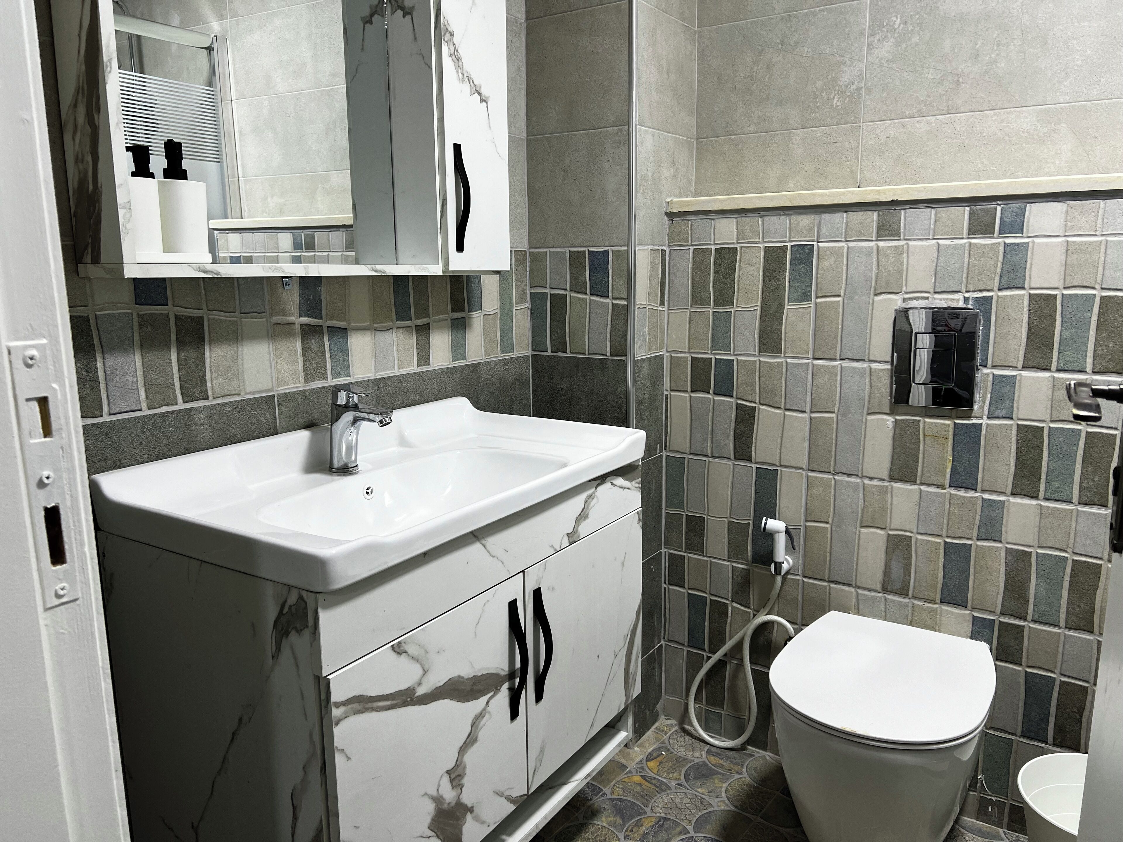 Un baño con lavamanos blanco, espejo, inodoro y zona de ducha.