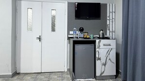 A compact kitchenette with a refrigerator, a microwave, a coffee maker, and a small cabinet. - Downtown inn  (Madaba)