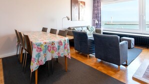 A room with a dining table, chairs, a sofa, and a view of the sea. - Apartment met Zeezicht in Oostende (Ostend)