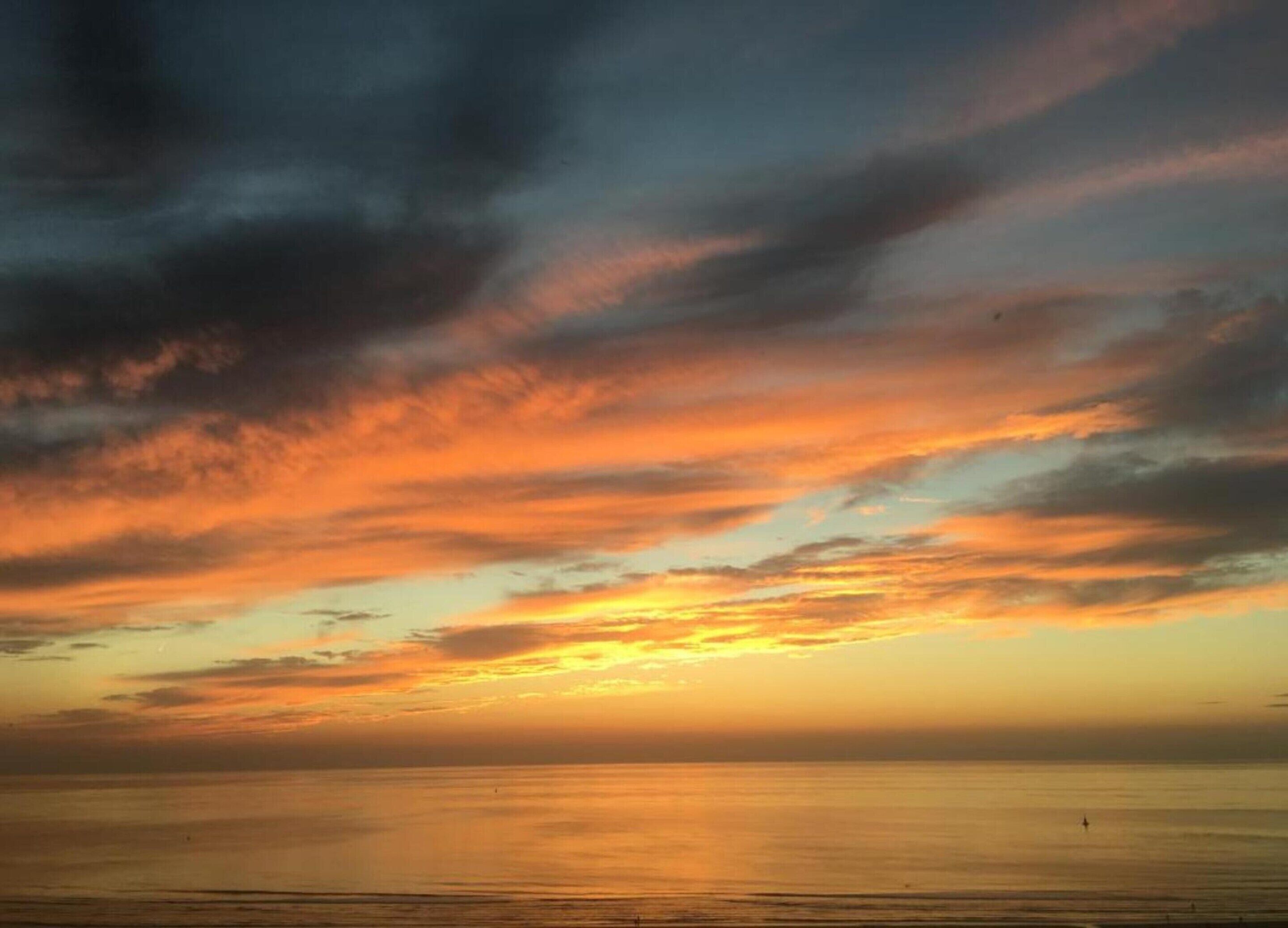 A sunset over a calm sea with a clear horizon.