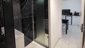 A modern bathroom with black marble walls and a white toilet.