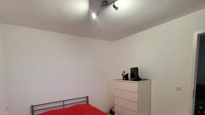 A bedroom with a single bed, a dresser, and a ceiling light.