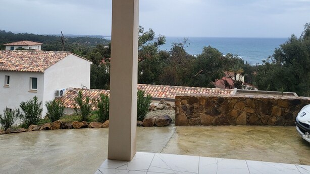 A covered patio with a view of the sea and surrounding buildings.