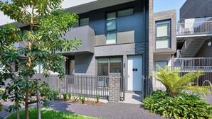 Un bâtiment moderne doté d’un toit plat, de grandes fenêtres et d’une entrée sécurisée par un portail.