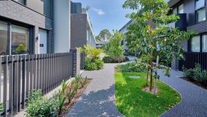 Un b âtiment moderne avec un chemin pavé, un petit arbre et une clôture.