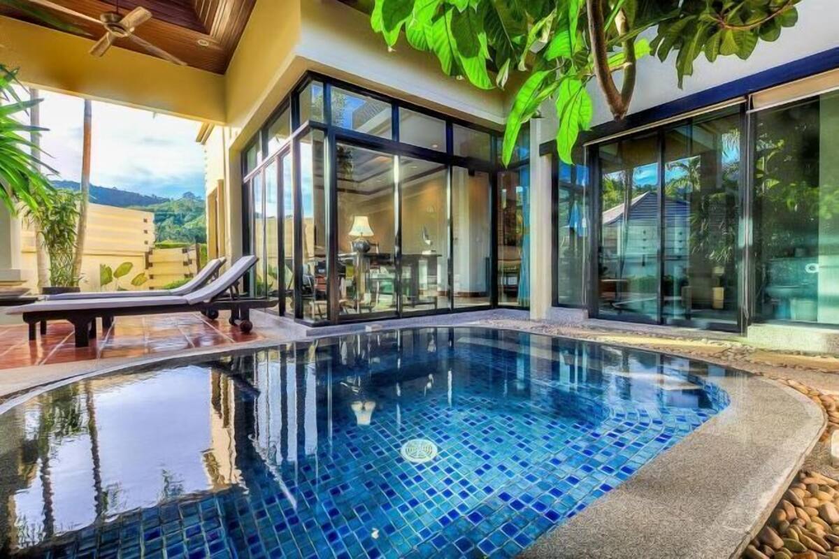 Una piscina interior moderna con paredes de vidrio, un área de descanso y vistas a la montaña.