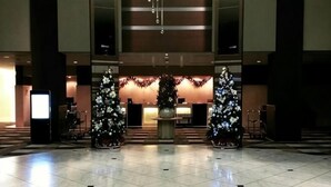 Un hall con suelo de baldosas, dos árboles de Navidad y una mesa de recepción.