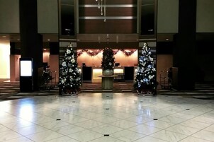 Un hall con suelo de baldosas, dos árboles de Navidad y una mesa de recepción.