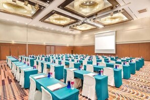 A conference room with rows of tables and chairs, a projector screen, and a carpeted floor. - ANA Crowne Plaza KUSHIRO by IHG (Kushiro City)