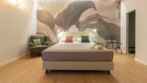 Um quarto moderno com uma cama grande, uma cadeira, um mural na parede e uma mesa de cabeceira.