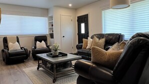 A modern living room with leather sofas, a coffee table, and a massage chair. - The Red Brick Retreat (Blackfoot)