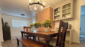 A dining area with a wooden table, benches, and potted plants. - The Red Brick Retreat (Blackfoot)