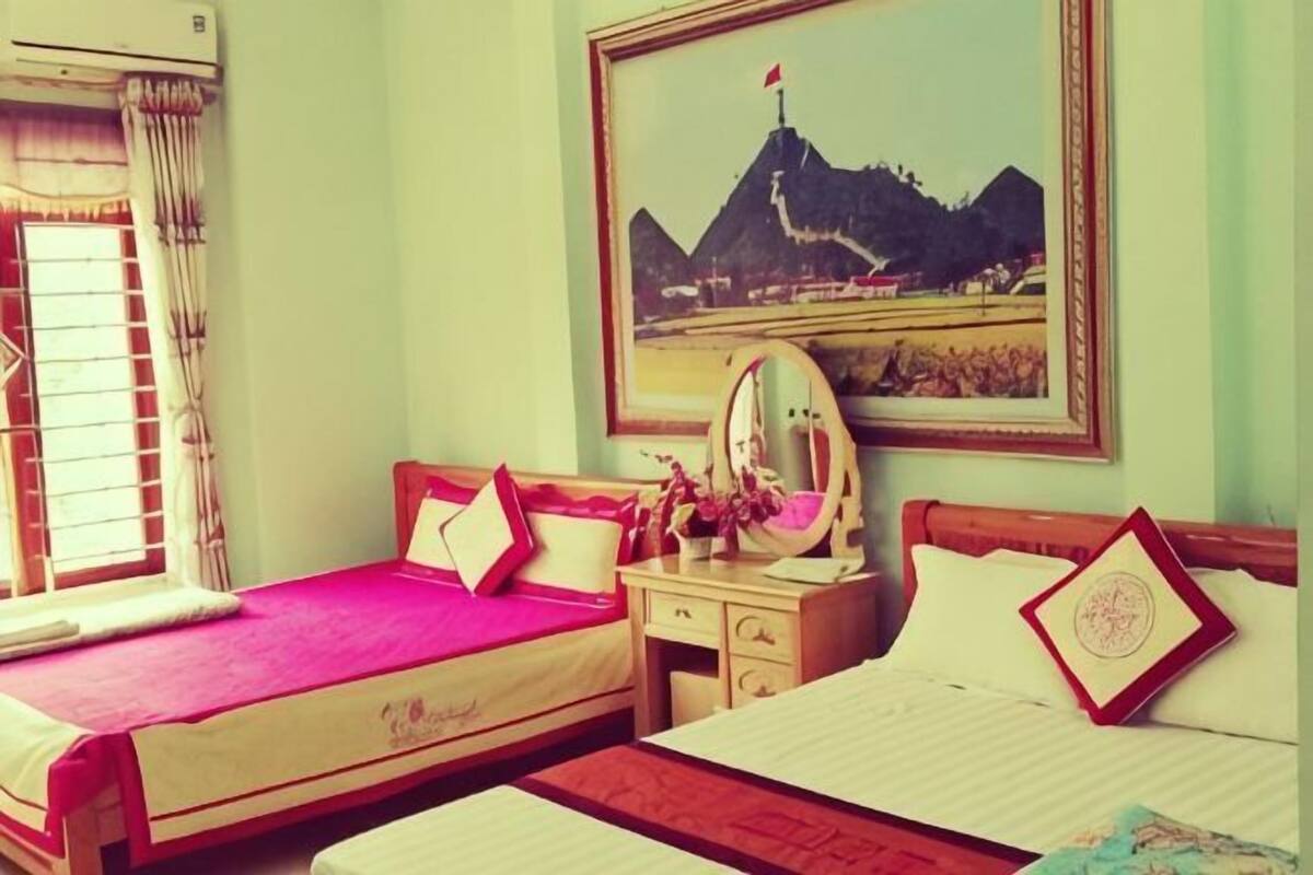 Habitación de hotel con dos camas, una ventana con cortinas, un aparador, un espejo y un cuadro en la pared.