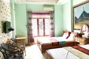 Un dormitorio con dos camas, un escritorio, una silla y una ventana con cortinas.