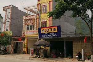 Un edificio con un letrero llamativo de JOTUN, un escaparate visible y una motocicleta estacionada afuera.