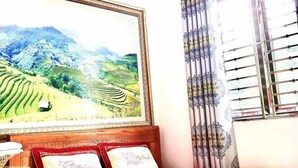Una habitación con cama, un cuadro enmarco de un paisaje y una ventana con cortinas.