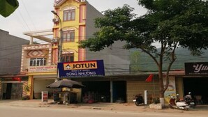 Vista de la calle con un edificio amarillo que muestra un letrero con 'JOTUN' y 'DAILY SON DUNG NHUONG'.