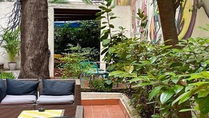 Un espacio al aire libre con mobiliario de mimbre y un patio con baldosas.