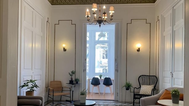 A spacious living room with a patterned floor, a sofa, two chairs, a small table, and a chandelier. - Sweet BCN Youth Hostel (Barcelona)