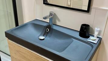 Casa de banho moderna com uma pia retangular, um espelho e um porta-toalhas.