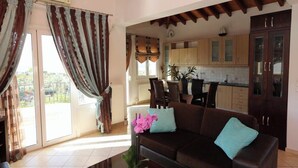 Ein Wohnzimmer mit braunem Sofa, einem Couchtisch und Blick auf einen Balkon.