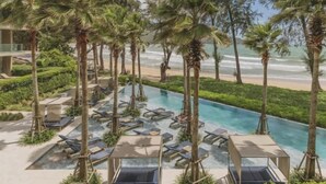 A pool area with lounge chairs, palm trees, and a view of the beach. - Twinpalms MontAzure Phuket (Phuket)