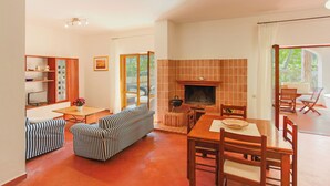 A spacious living area with a fireplace, a dining table, and striped sofas.