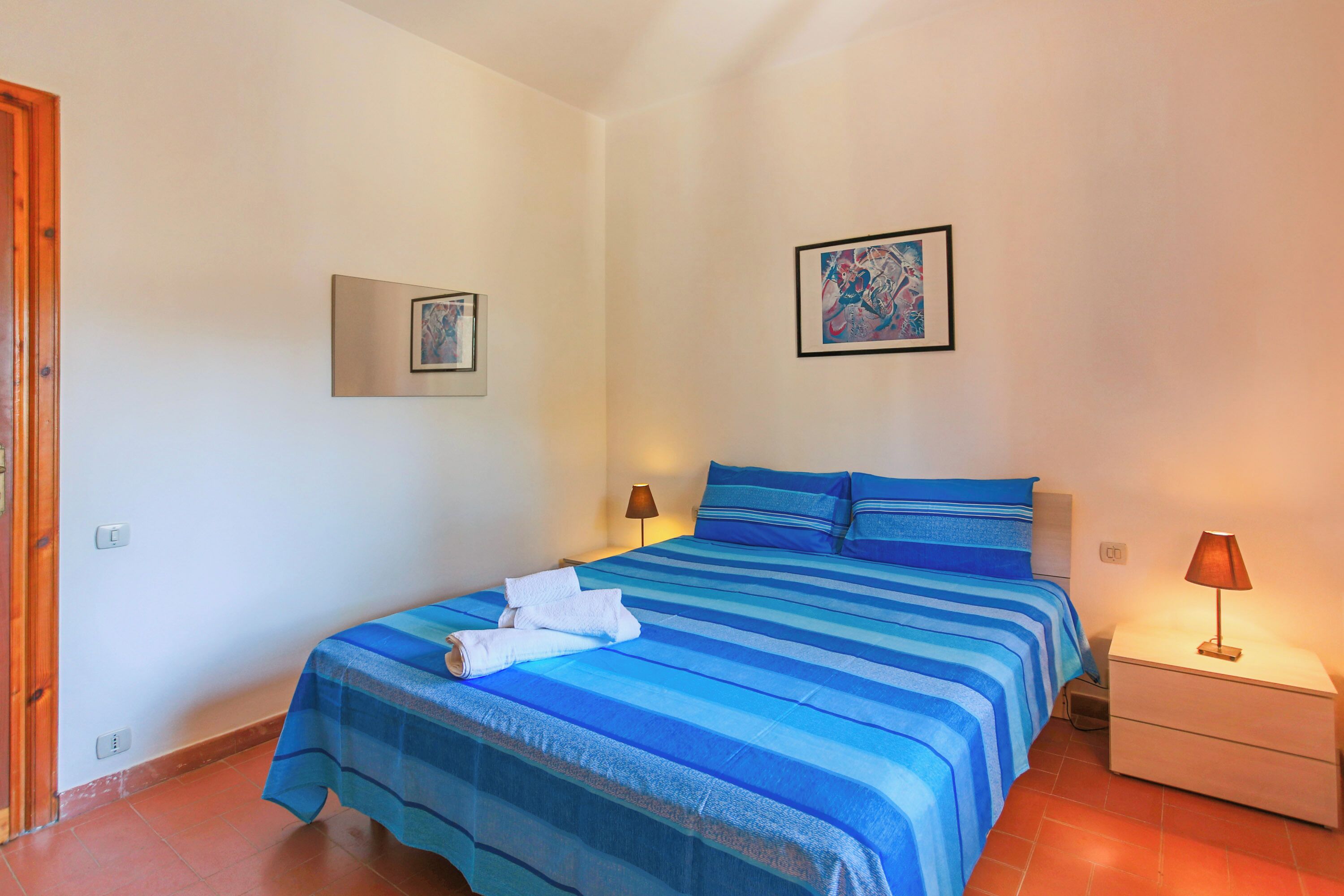 Une chambre à coucher avec un grand lit, deux tables de chevet et deux lampes fixées au mur.
