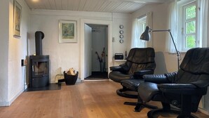 Una sala acogedora con una estufa de leña, sillones de cuero y una lámpara.