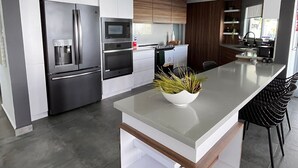 Een moderne keuken met een centraal eiland, roestvrijstalen apparatuur en een minimalistisch design.