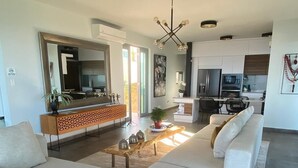 Een moderne woonkamer met een modulaire bank, een houten salontafel en een keuken op de achtergrond.