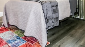 Ein Schlafzimmer mit einem Bett, grünen Vorhängen, einer Lampe und einem farbenfrohen Teppich.