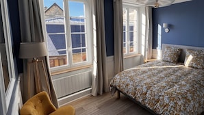 A bedroom with a bed, a chair, a lamp, and a window with curtains. - House for 10 people in the center of Sainte Mère Eglise (Sainte-Mère-Église)