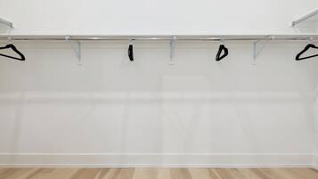 Een kamer met een houten vloer en een kledingrek met zwarte hangers.