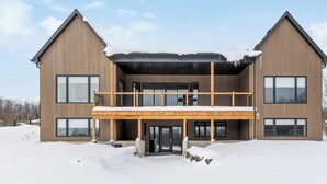 Un edificio de madera de dos pisos con un balcón y ventanas grandes, rodeado de nieve.