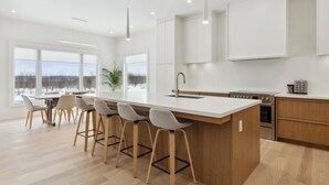 Una cocina moderna con una isla grande, taburetes de bar y vistas al exterior.