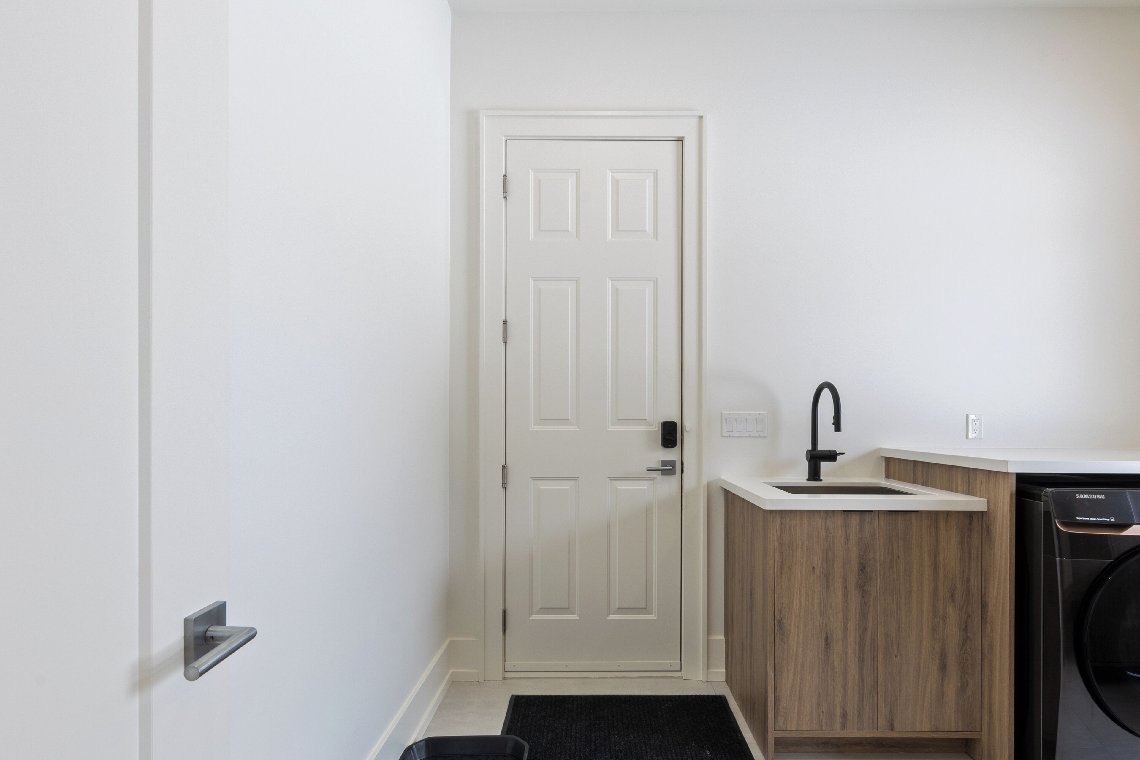 A compact kitchen with a white door, a sink, and a dishwasher.