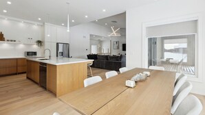 Una cocina moderna con armarios de madera, una isla central y un comedor con mesa y sillas de madera.