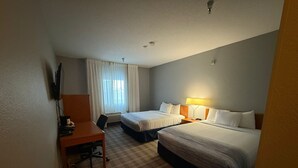 A hotel room with two beds, a desk, a TV, and a window with curtains.