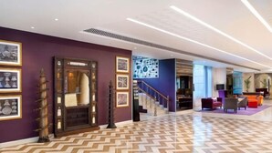 A hotel lobby with a herringbone floor pattern, a staircase, and a reception area. - Grand Mercure Bengaluru at Gopalan Mall, An Accor Hotels Brand (Bengaluru)