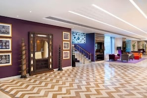 A hotel lobby with a herringbone floor pattern, a staircase, and a reception area. - Grand Mercure Bengaluru at Gopalan Mall, An Accor Hotels Brand (Bengaluru)
