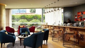 A modern interior with a bar area, seating, and a view of greenery. - Grand Mercure Bengaluru at Gopalan Mall, An Accor Hotels Brand (Bengaluru)