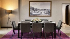 A dining area with a table set for six, a framed landscape painting above, and a floor lamp to the left. - Grand Mercure Bengaluru at Gopalan Mall, An Accor Hotels Brand (Bengaluru)