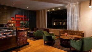 A cozy lounge area with a wooden coffee table, green upholstered chairs, and a leather sofa. - Grand Mercure Bengaluru at Gopalan Mall, An Accor Hotels Brand (Bengaluru)