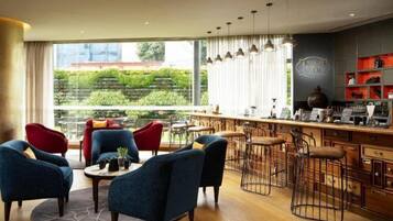 A modern interior with a bar area, seating, and a view of greenery.