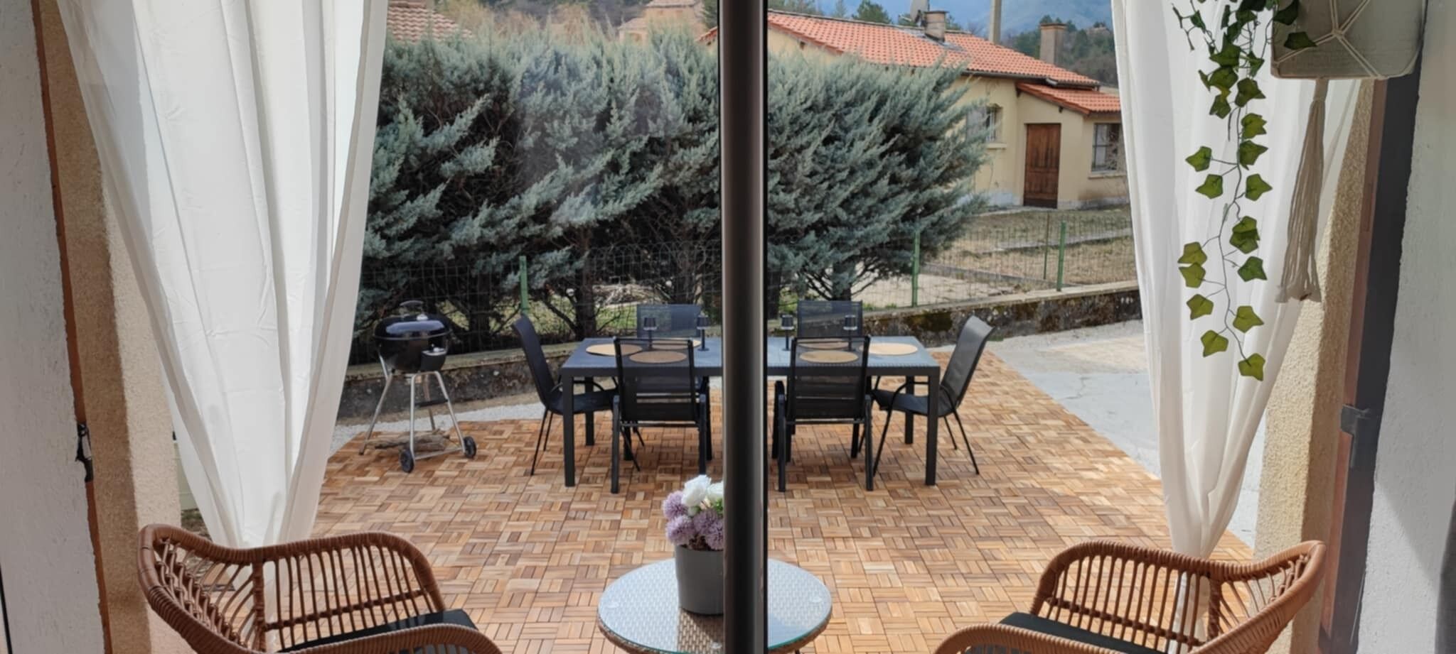 Un patio con tavolo e sedie, un barbecue e una pianta in vaso.