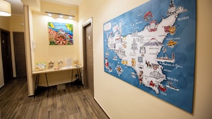 A hallway with a map of Italy on the wall, a desk with items on it, and a door. - Terra d'Agrumi Rooms (Catania)
