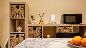 A dining area with wicker baskets, a microwave, a plate of oranges, and a decorative item on the table. - Terra d'Agrumi Rooms (Catania)