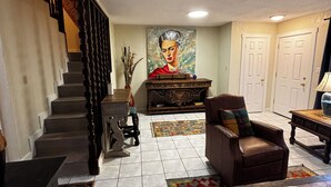 A spacious living room with a staircase, a large painting, a leather armchair, and a coffee table. - The Luxury Rustic Home, exceeding your expectations, not your budget! (Laredo)