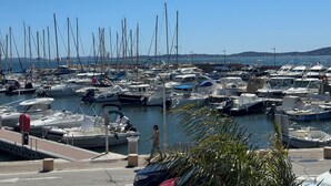 Un port de plaisance où de nombreux bateaux sont amarrés, un ciel dégagé et une côte lointaine.